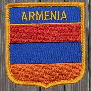 May include: A fabric patch with a gold border and the word "ARMENIA" in yellow letters. The patch features the colors of the Armenian flag: red, blue, and orange.