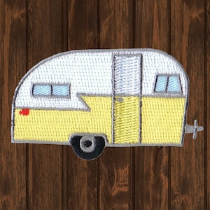 May include: An embroidered patch depicting a vintage camper in yellow and white. The camper has a single door and two windows. The patch is ideal for adding a retro touch to any project.