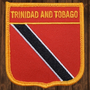 May include: A red, black, and white embroidered patch with the text "TRINIDAD AND TOBAGO" in yellow. The patch is surrounded by a yellow border.