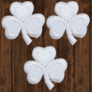 May include: Three white felt shamrock patches. The shamrocks are embroidered with a raised design.