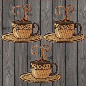 Può includere: Tre toppe ricamate raffiguranti tazze di caffè con manici marroni e vapore vorticoso. Le tazze poggiano su piattini abbinati, con cuciture decorative e una combinazione di colori marrone chiaro e scuro. Lo sfondo è un motivo a doghe di legno.
