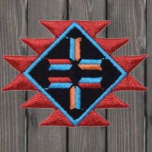 Puede incluir: Un parche bordado rojo, azul y naranja con un diseño geométrico. El parche tiene la forma de una estrella con un diamante en el centro.