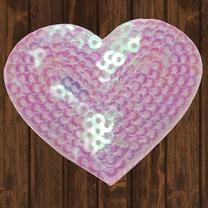 May include: A pink iridescent heart-shaped sequin patch. The sequins are arranged in a pattern and have a shimmery finish.