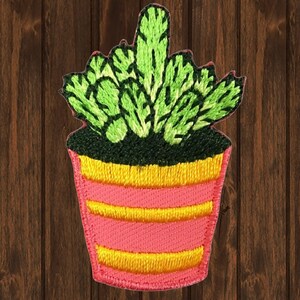 Puede incluir: Una planta suculenta bordada de color verde en una maceta rosa con rayas amarillas. La maceta está llena de tierra verde oscura.