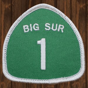以下が含まれることがあります： 緑と白の刺繍パッチで、「BIG SUR」というテキストと中央に「1」という数字があります。