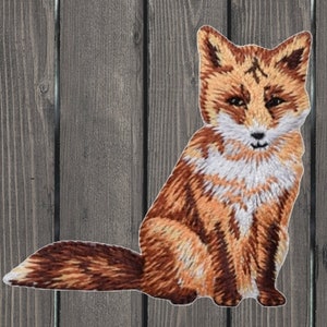 May include: A brown and white embroidered fox patch. The fox is sitting with its tail curled behind it. The patch is perfect for adding a touch of whimsy to clothing, bags, or other crafts.