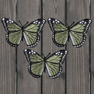 Può includere: Tre toppe ricamate a forma di farfalla verde con contorni neri. Le farfalle hanno accenti bianchi sulle ali.