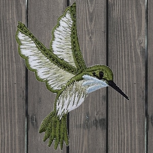 Puede incluir: Parche de aplique de colibrí bordado en verde y blanco. El colibrí está en vuelo con las alas extendidas. El parche es perfecto para agregar un toque de naturaleza a tus manualidades.