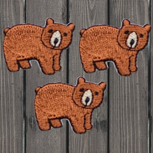 Puede incluir: Tres parches bordados de osos marrones. Los osos están de pie sobre sus cuatro patas y tienen un diseño simple.