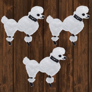 May include: Three white poodle patches with black collars and feet are arranged on a brown wooden background. The patches are embroidered with a textured appearance, showcasing the poodle's distinctive shape and style.