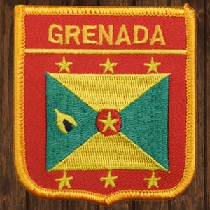 May include: A red, yellow, and green embroidered patch with the word "GRENADA" in yellow lettering. The patch features the flag of Grenada with six yellow stars surrounding the flag.