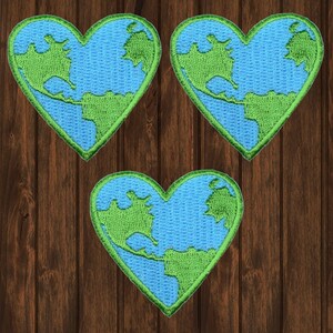 Puede incluir: Tres parches bordados en forma de corazón, cada uno representando un contorno azul y verde de la Tierra.