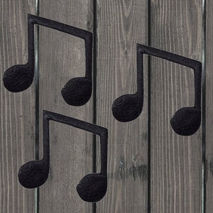 Puede incluir: Cuatro formas de notas musicales de metal negro sobre un fondo de madera.