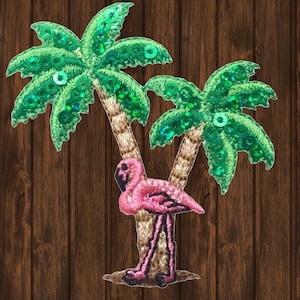 May include: A pink flamingo standing next to two green palm trees with sequins. The palm trees and flamingo are embroidered.