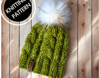 May include: A knitted green beanie with a large white and gray faux fur pom-pom. The hat has a cable knit design and a small brown leather tag. The words "KNITTING PATTERN" are in a black circle.