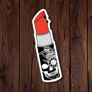May include: A black and white sticker of a lipstick tube with a skull and floral design. The lipstick is red and the skull has a sunflower in its eye.