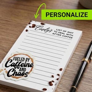 Puede incluir: Un bloc de notas blanco con páginas rayadas, con el texto "Cindy's" y "Lista de mierda para lidiar después del café". Una pegatina con mancha de café dice "Impulsado por cafeína y caos". Granos de café esparcidos alrededor del bloc de notas. Un bolígrafo negro descansa al lado.