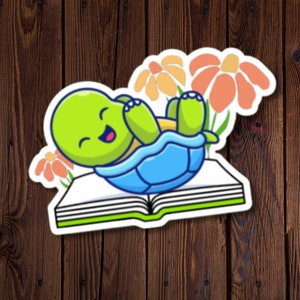 Sticker tortue lunatique mignonne sur un livre ouvert, adorable autocollant en vinyle résistant à l'eau pour les amoureux des tortues, de la nature et des livres