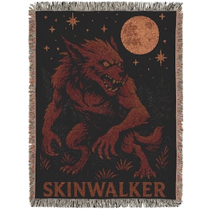 May include: Black woven throw blanket featuring a red werewolf under a full moon and stars. The word "SKINWALKER" is printed at the bottom. The blanket has a fringed edge.