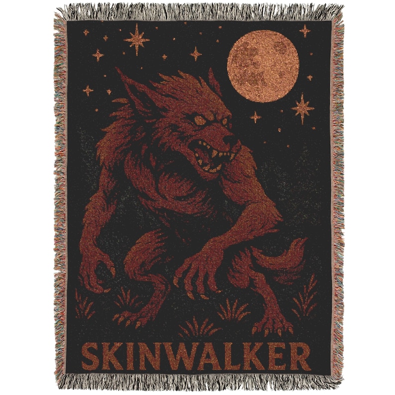 May include: Black woven throw blanket featuring a red werewolf under a full moon and stars. The word "SKINWALKER" is printed at the bottom. The blanket has a fringed edge.
