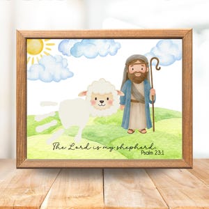 Op de afbeelding: Een ingelijste aquarelprint met een cartoonillustratie van een herder met een staf, een schaap, zon en wolken. De tekst "The Lord is my shepherd. Psalm 23:1" staat eronder. Het frame is van hout.