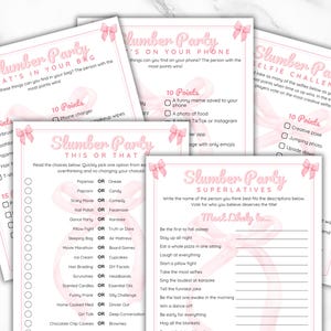 May include: Pink and white printable game cards for a slumber party. The cards have a pink ribbon design and include games like "What's in your bag?", "This or That", "Slumber Party Superlatives", and "Selfie Challenge".