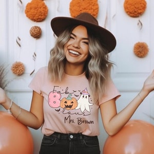 May include: A pink t-shirt with a graphic of a ghost wearing a witch hat and a pumpkin with the text "Fabulous" and "Mrs. Brown".