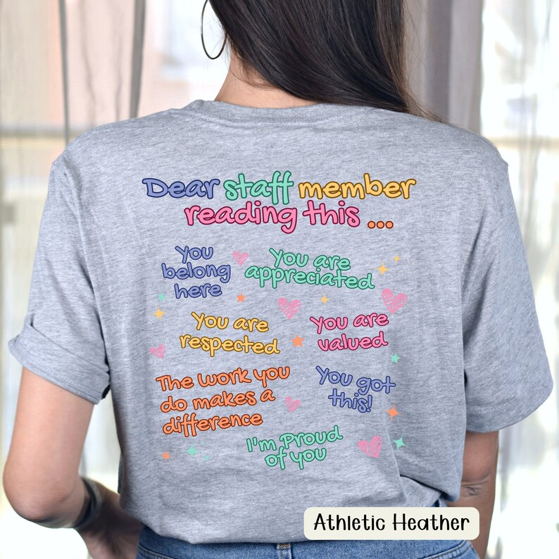 K&ouml;nnte beinhalten: Graues Athletic Heather T-Shirt mit farbenfrohem Text, der lautet: "Liebe/r Mitarbeiter/in, der/die dies liest..." gefolgt von positiven Affirmationen. Auf dem Shirt steht auch "Athletic Heather" am unteren Rand.