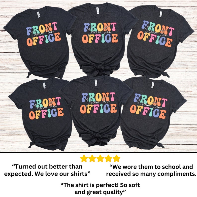 K&ouml;nnte beinhalten: Sechs dunkelgraue T-Shirts mit den Worten "FRONT OFFICE Dream Team" in einer farbenfrohen Retro-Schrift. Die Shirts sind auf einer hellen Holzmaserung angeordnet. Der Text ist in einem Regenbogen von Farben gehalten, darunter Blau, Orange und Rosa.