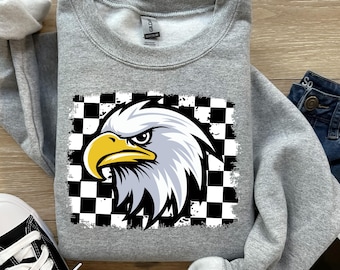May include: A gray sweatshirt with a black and white checkered pattern and a white eagle head with a yellow beak and eyes.
