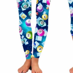 May include: Blue leggings with a pattern of colorful bingo balls and cards. The balls have numbers and letters on them. The cards have the word "Bingo" on them.