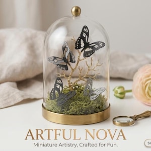 Peut inclure: Une cloche en verre avec une base dorée abrite quatre figurines de papillons sur une branche dorée, posées sur de la mousse verte. La cloche est surmontée d'un bouton doré. Le texte "ARTFUL NOVA" et "Miniature Artistry, Crafted for Fun" sont affichés en dessous.