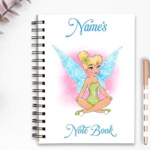 May include: A white notebook with a spiral binding. The cover features a colorful illustration of Tinker Bell, a fairy with green wings, sitting with her legs crossed. The text "Name's Note Book" is written in blue cursive.