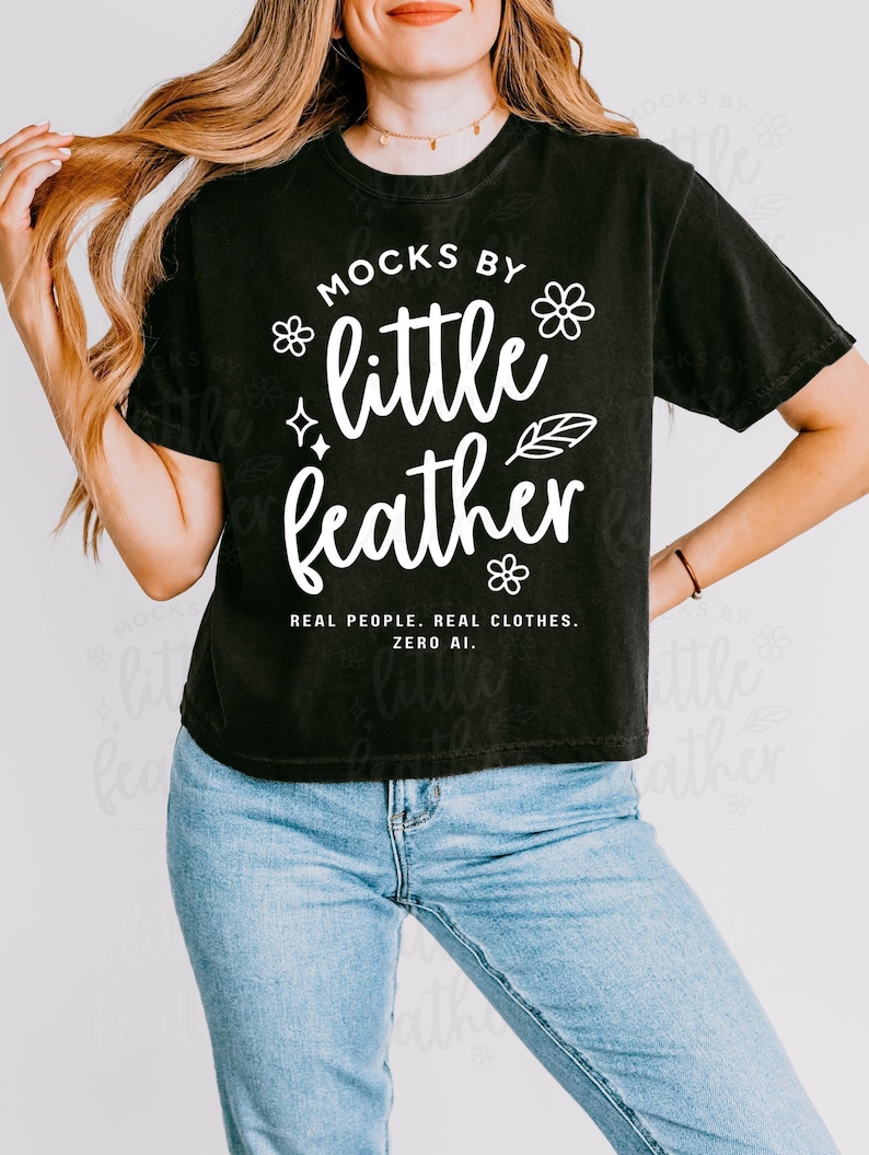Woman wearing a black comfort colors 3023cl t-shirt with bold white text that says 'Mocks by Little Feather – Real People. Real Clothes. Zero AI.' surrounded by doodle-style flowers and feathers. Trendy Etsy-style mockup featuring real model photography for print-on-demand sellers.