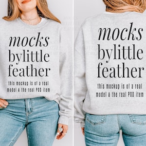 May include: A light gray crewneck sweatshirt featuring black text that reads mocks bylittle feather and this mockup is of a real model & the real POD item. The garment is shown from both the front and back views on a person wearing blue jeans.