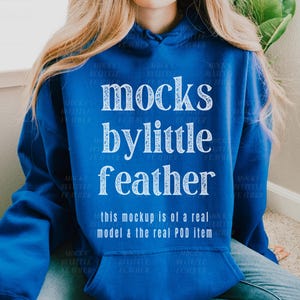 Puede incluir: Una sudadera con capucha azul real con el texto "mocks bylittle feather" en blanco. El texto "this mockup is of a real model & the real POD item" tambi&eacute;n est&aacute; impreso en blanco.