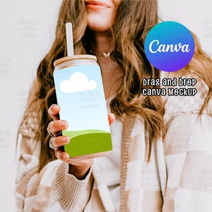 Puede incluir: Un vaso reutilizable blanco y verde con un diseño de nube y hierba. El vaso tiene una tapa de bambú y una pajita. El texto "Canva" es visible en el fondo.