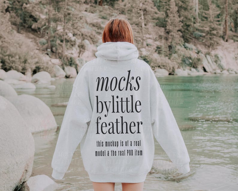Puede incluir: Una sudadera con capucha blanca con el texto "mocks by little feather this mockup is of a real model & the real POD item" impreso en la parte posterior.