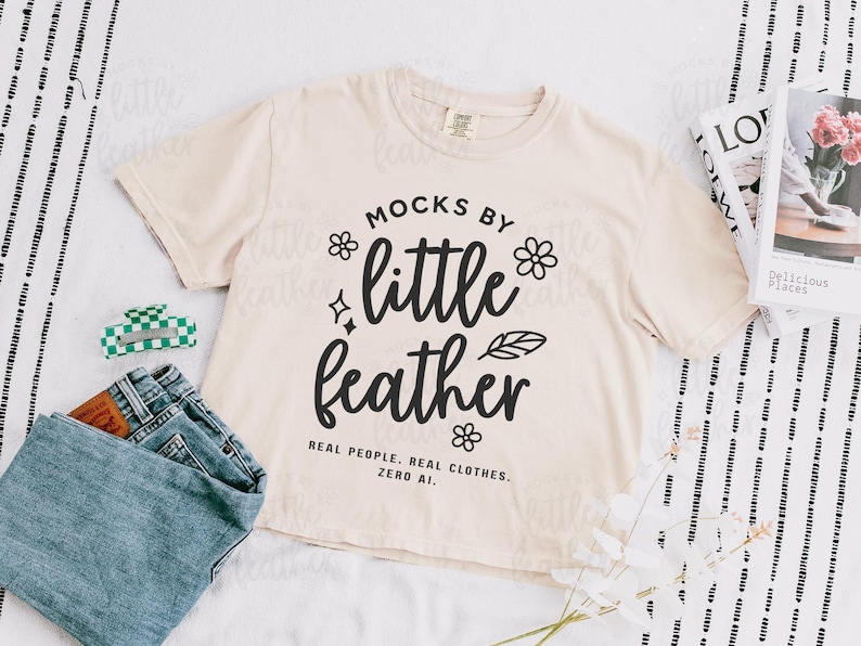 an ivory comfort colors 3023cl t-shirt with bold white text that says 'Mocks by Little Feather – Real People. Real Clothes. Zero AI.' surrounded by doodle-style flowers and feathers. Trendy Etsy-style mockup featuring real model photography for print-on-demand sellers.