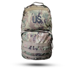 Peut inclure: Un sac à dos camouflage avec un motif multicolore composé de vert, de marron et de beige. L'avant du sac affiche les lettres US en bleu foncé. Il comprend une poignée supérieure, un compartiment principal zippé et deux sangles horizontales.