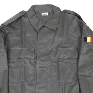 K&ouml;nnte beinhalten: Eine gr&uuml;ne Milit&auml;rjacke mit einem belgischen Flaggen-Patch am &Auml;rmel. Die Jacke hat zwei gro&szlig;e Taschen auf der Vorderseite und einen Knopfverschluss. Das Etikett am Kragen lautet "54M".