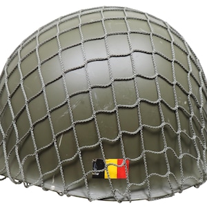 Pode incluir: Capacete militar verde-oliva com rede de camuflagem. O capacete apresenta um pequeno emblema da bandeira belga. A rede é de cor cinza claro. Capacete de estilo militar clássico.