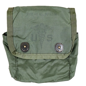Puede incluir: Un estuche de nailon verde oliva para botiquín de primeros auxilios individual con cierre de solapa y dos botones de presión de metal negro. El frente muestra un símbolo de caduceo impreso sobre las letras U S y el texto FIRST AID KIT, INDIVIDUAL.