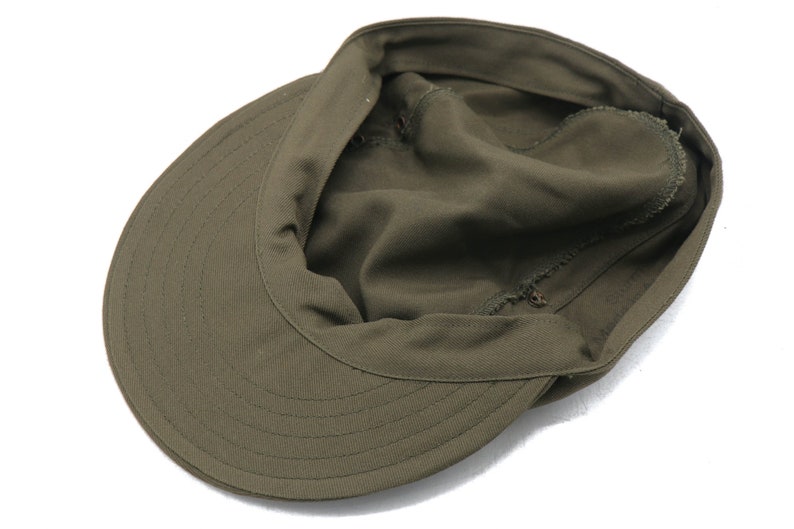 K&ouml;nnte beinhalten: Eine gr&uuml;ne Milit&auml;rkappe mit einem Schirm und einer umklappbaren Klappe. Die Kappe ist aus weichem Baumwollstoff.