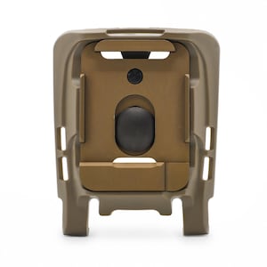 May include: A tan-coloured tactical holster mount featuring a rectangular frame with a central sliding plate and a circular black button. The structure includes vertical side slots and a reinforced base, designed for secure equipment attachment.