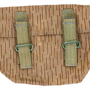 Puede incluir: Una bolsa de lona marrón con dos correas y hebillas verdes. La bolsa tiene un patrón de camuflaje.