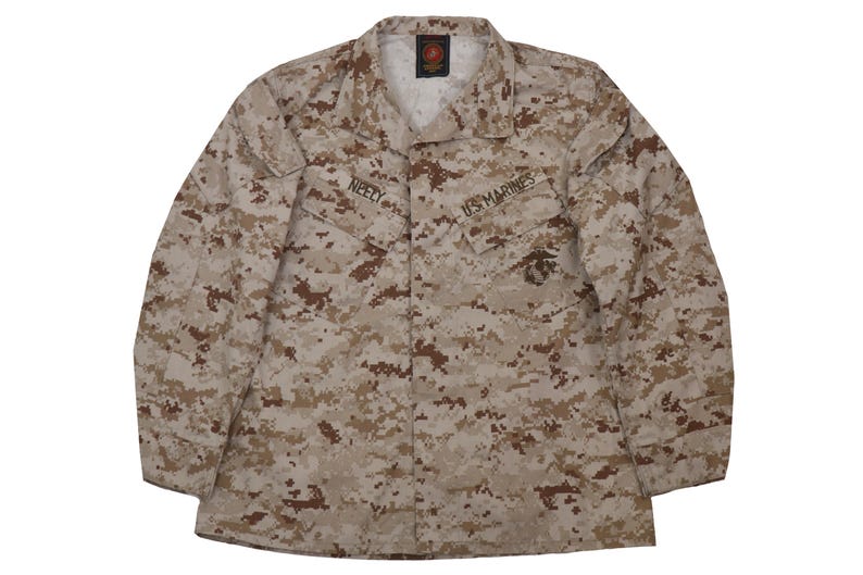Puede incluir: Una chaqueta militar de camuflaje marr&oacute;n y beige con las palabras "US Marines" y "NEELY" bordadas en la parte delantera.