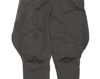 May include: Dark olive green breeches featuring a high-waisted design with a button closure, a zippered fly, and side pockets. The trousers have a flared hip silhouette that tapers down to the lower legs, which include buttoned cuffs at the ankles.