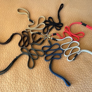 May include: A collection of ten colorful woven straps with metal clasps. The straps are arranged in a circle on a brown surface.