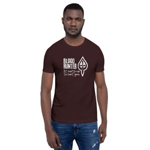 Może przedstawiać: Marmurowy t-shirt z białym nadrukiem graficznym, na którym widnieje napis "Blood Hunter" i "It hurts me to hurt you".